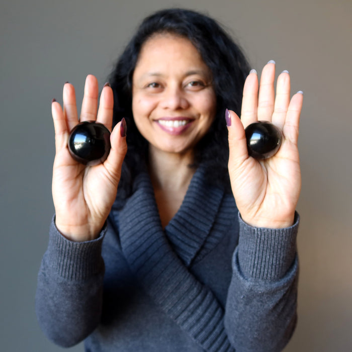sheila of satin crystals holding two black obsidian spheres in her palms
