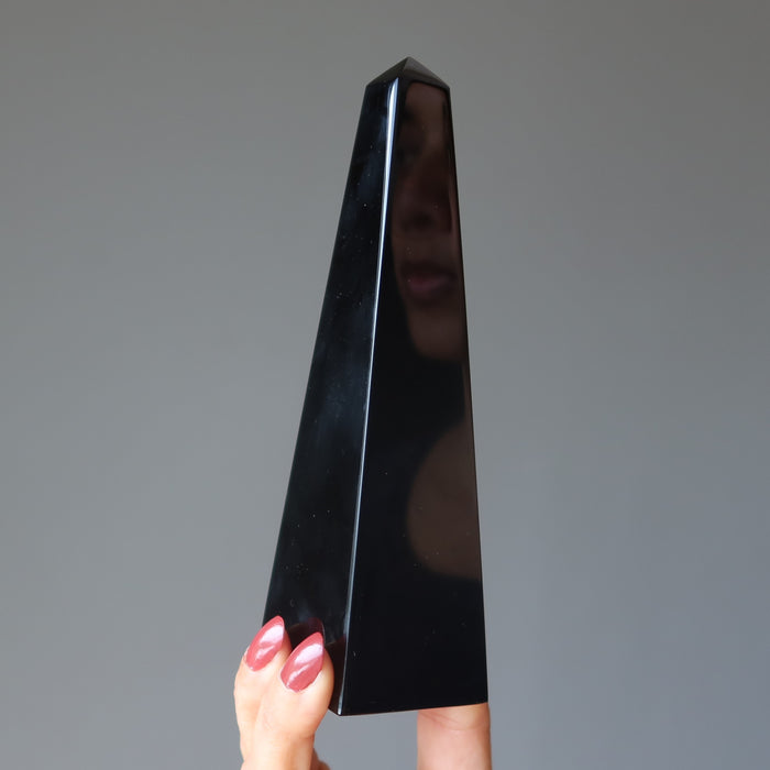 hand holding black obsidian obelisk