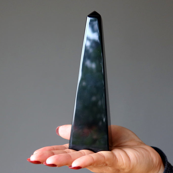 palm holding black obsidian obelisk