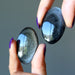 holding 2 oval Silver Sheen Obsidian cabochons 