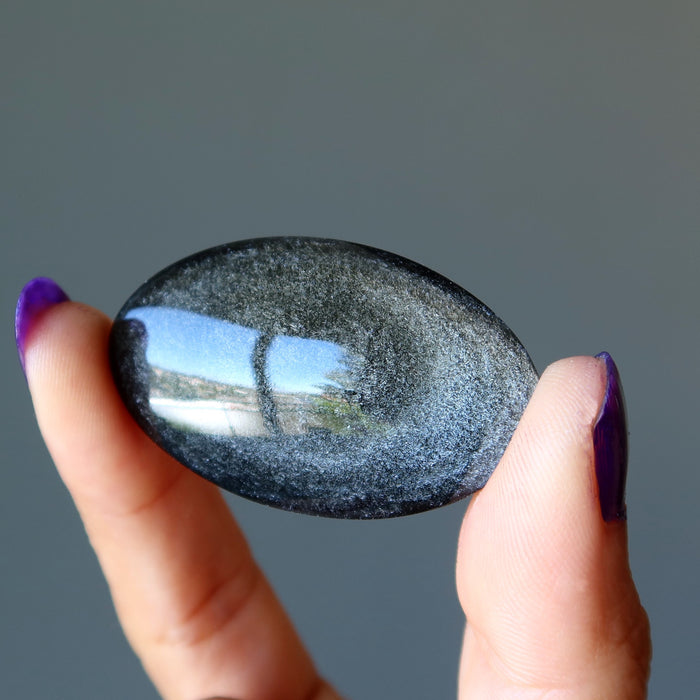 holding oval Silver Sheen Obsidian cabochon