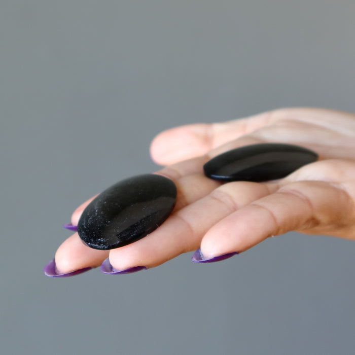 2 oval Silver Sheen Obsidian cabochons on the palm