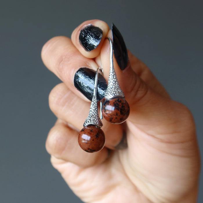 hand holding mahogany obsidian in silver dangle earrings