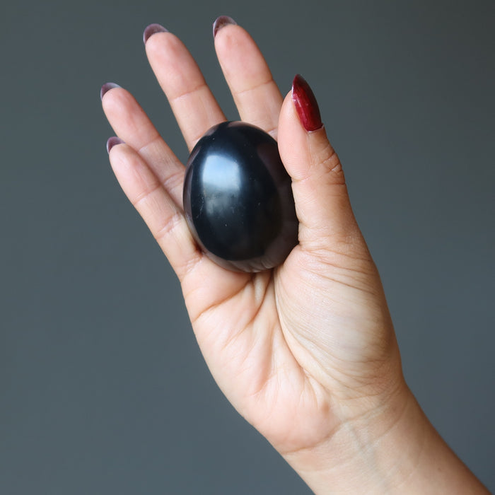 hand holding black obsidian egg