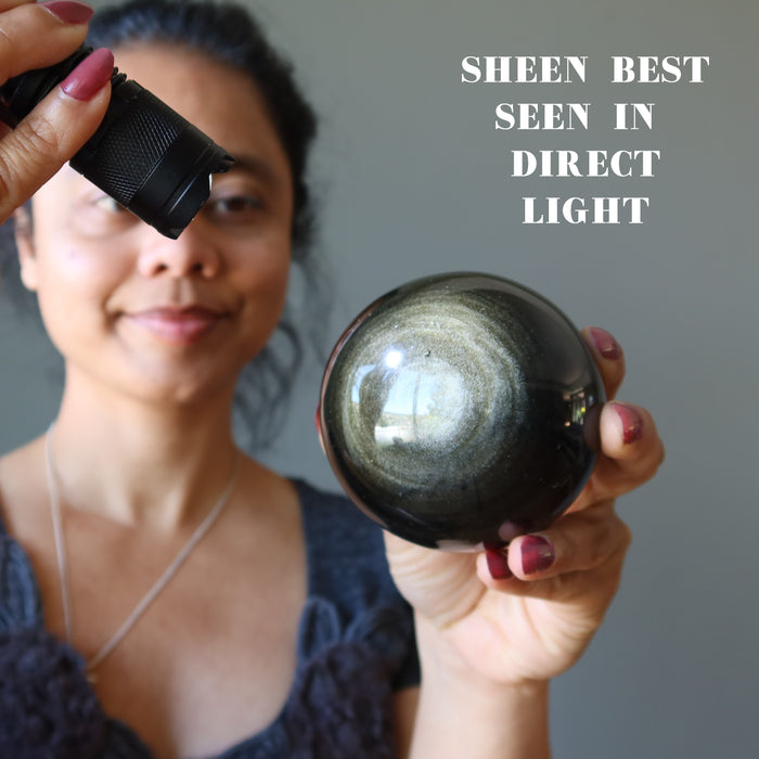sheila of satin crystals shining flash light on Obsidian Sphere to see the gold sheen