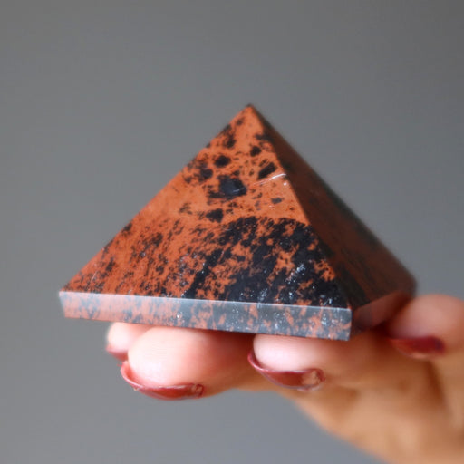 hand holding mahogany obsidian pyramid