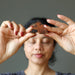 woman holding mahogany obsidian pyramid at third eye chakra