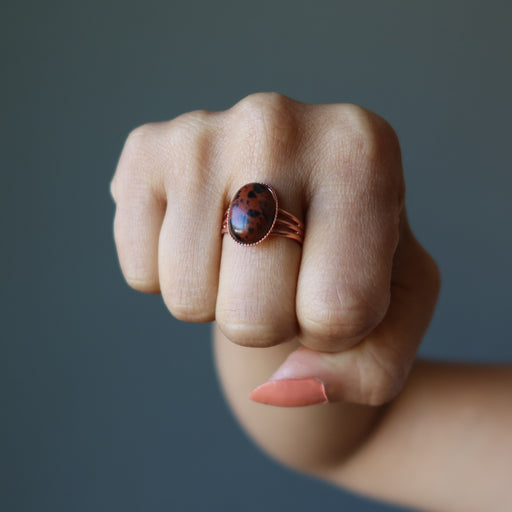 fist wearing mahogany obsidian oval in copper adjustable ring