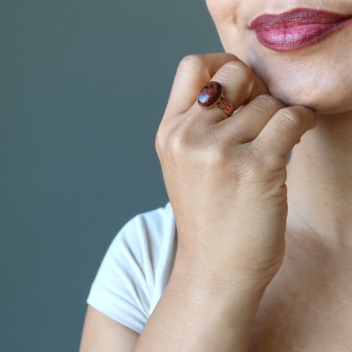 hand on chin wearing mahogany obsidian oval in copper adjustable ring
