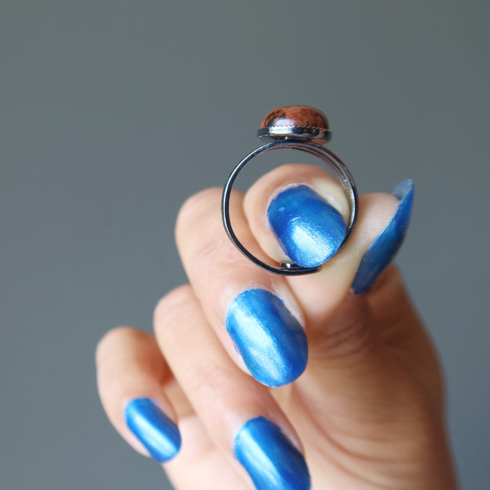 hand holding mahogany obsidian oval in gunmetal adjustable ring