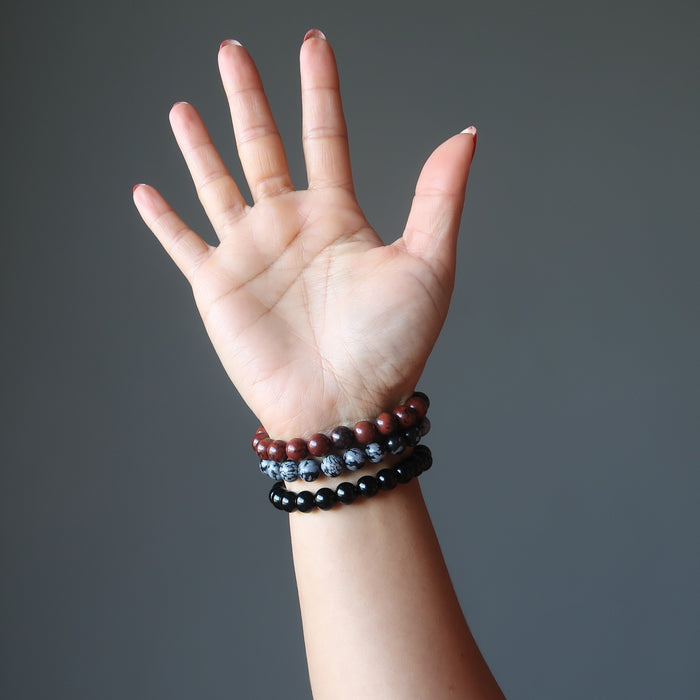 a lady models the obsidian bracelet three piece set on her wrist