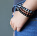 a lady models the black mahogany and snowflake obsidian triple set against her jeans