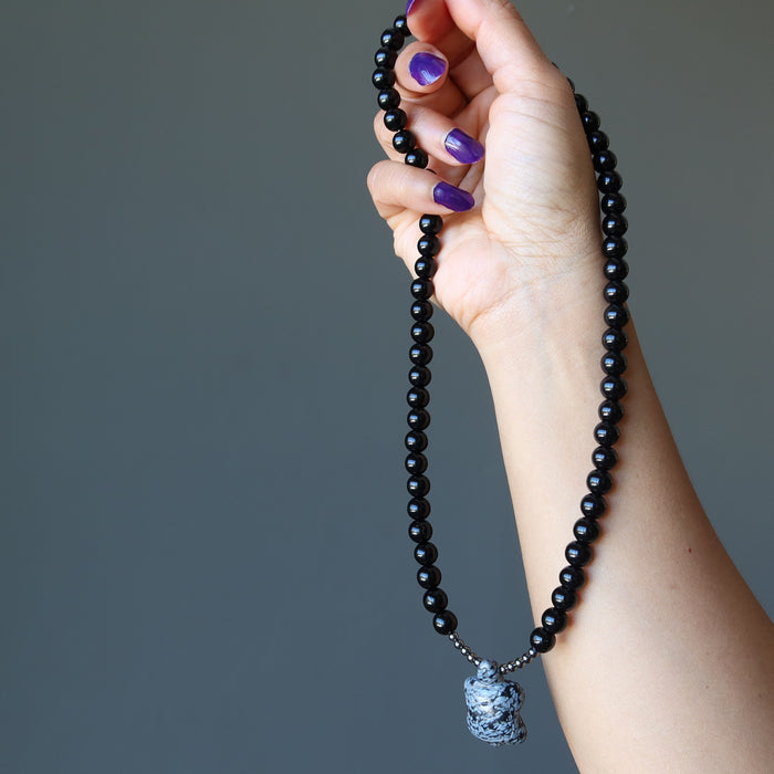 hand holding snowflake obsidian turtle necklace
