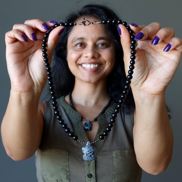 woman holding snowflake obsidian turtle necklace