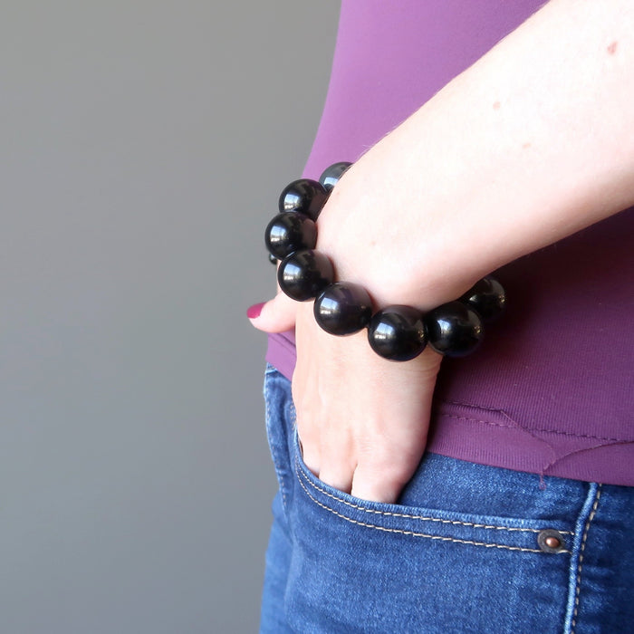 woman's hand in jeans pocket wearing rainbow obsidian beaded stretch bracelet