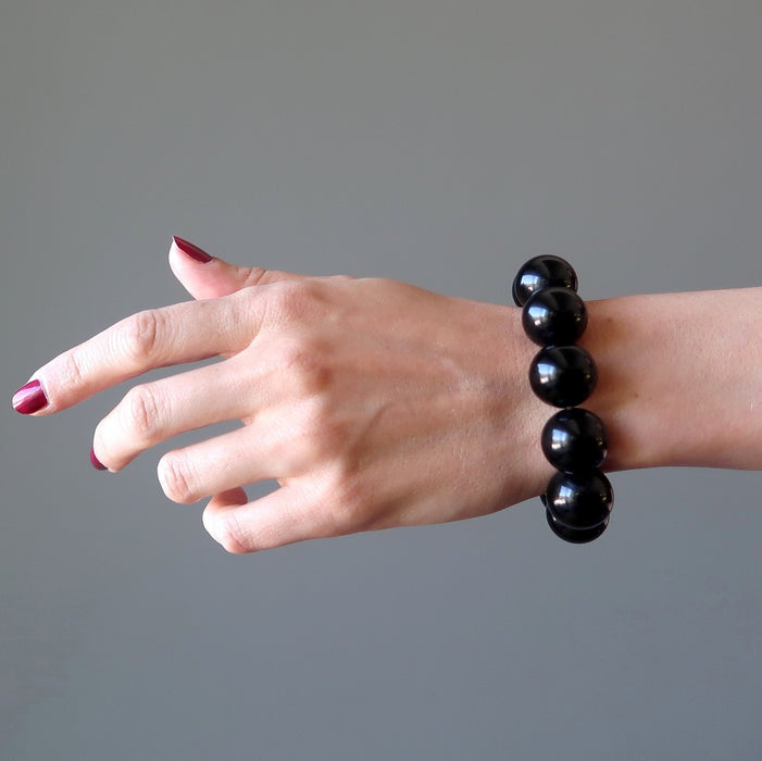woman's hand wearing rainbow obsidian beaded stretch bracelet