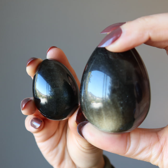 hands holding two sheen obsidian eggs