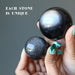 holding two differnt size Silver Sheen Obsidian Spheres one on each hand