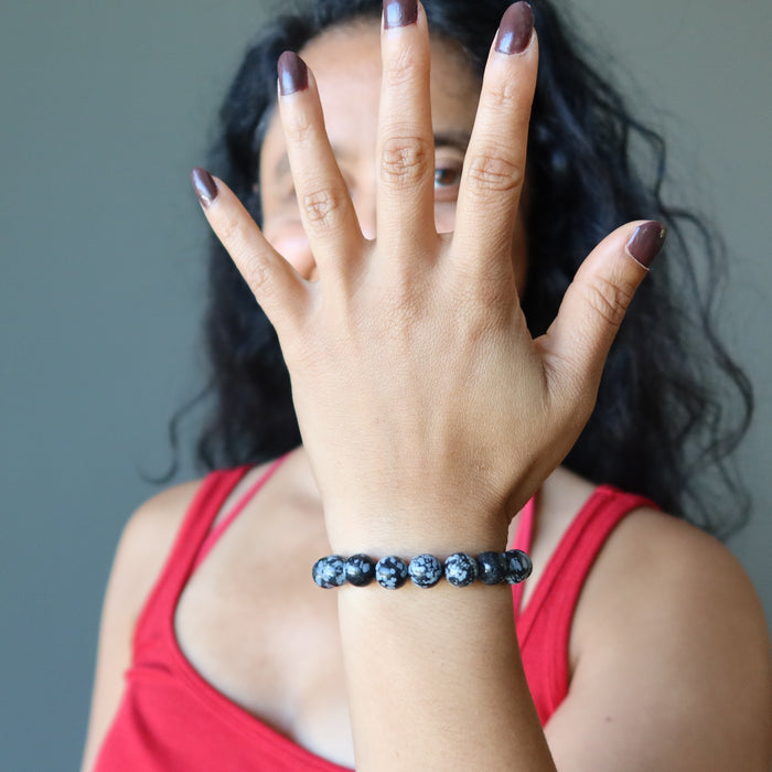showing a model raising arm wearing Snowflake Obsidian Bracelet 