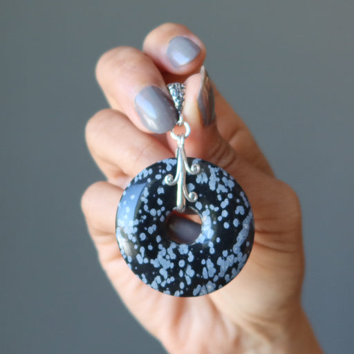 hand holding snowflake obsidian donut pendant