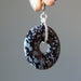 hand holding snowflake obsidian donut pendants