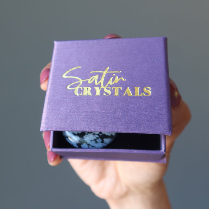 holding Snowflake Obsidian Pendant in a satin crystal purple jewery box