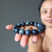 sheila of satin crystals with a  round spiderweb obsidian stretch bracelet in the palm of her hand
