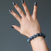 female hand raised up and wearing  round spiderweb obsidian stretch bracelet