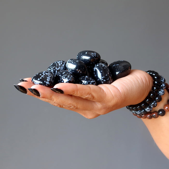 hand holding black and gray snowflake obsidian tumbled stones