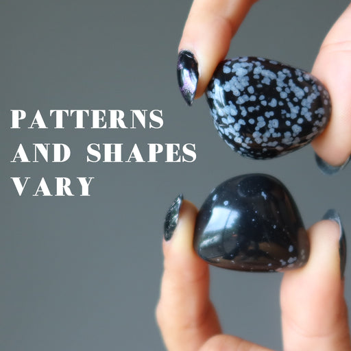hand two snowflake obsidian tumbled stones to show patterns vary