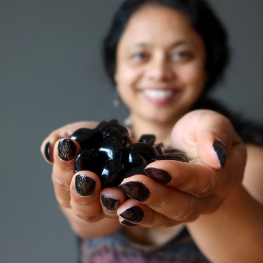 sheila of satin crystals holding 43 black obsidian tumbled stones
