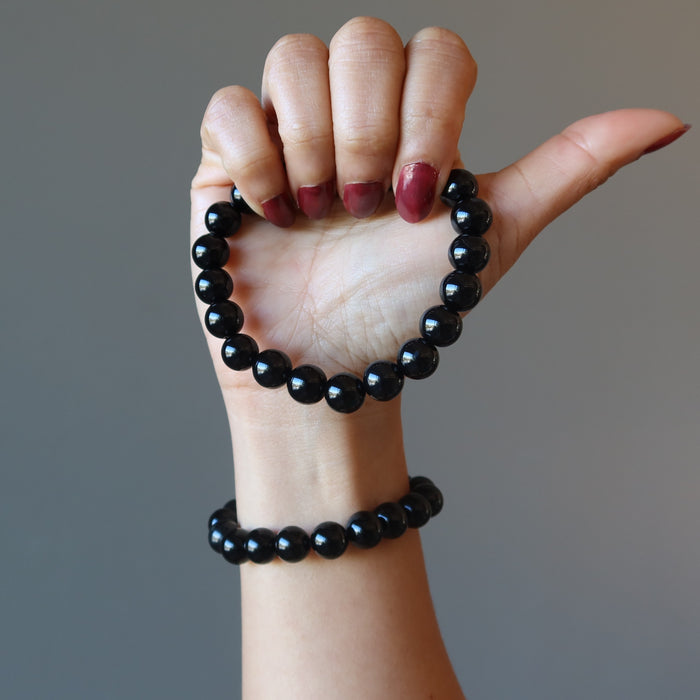 hand wearing and holding black onyx bracelet