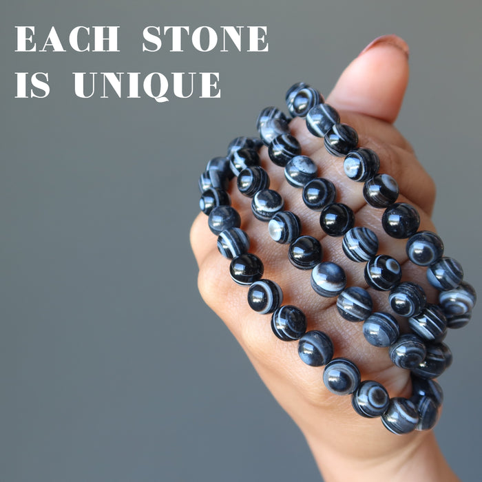 hand holding several bullseye onyx bracelets to show each stone is unique