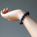 hand wearing a matte and polished glossy beaded round black onyx stretch bracelet