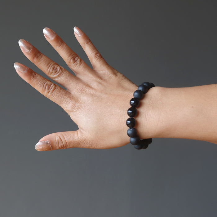 hand wearing a matte and polished glossy beaded round black onyx stretch bracelet
