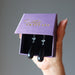 hand holding black onyx earrings in purple satin crystals gift box
