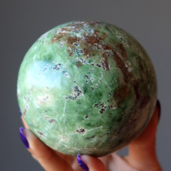 hand holding green opal sphere 