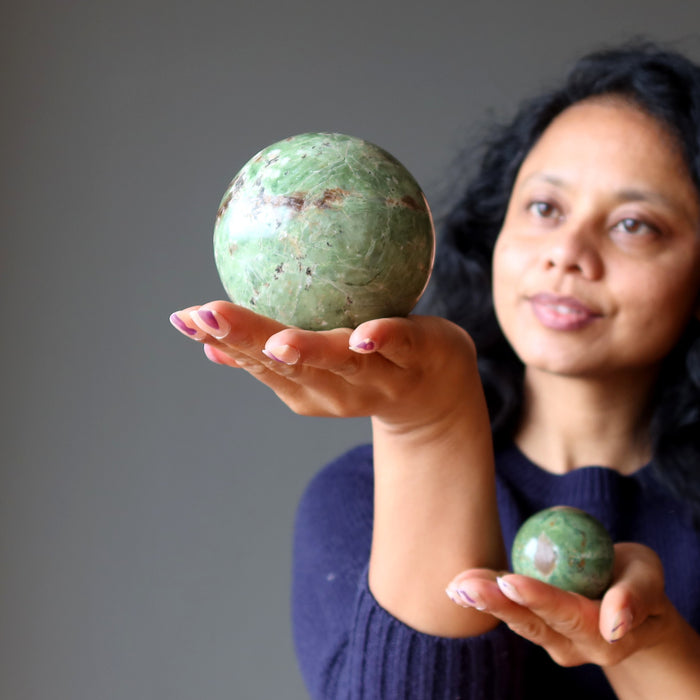 sheila of satin crystals holding two green opal spheres