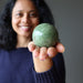sheila of satin crystals holding green opal sphere 