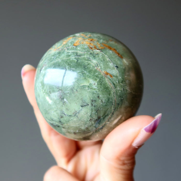 hand holding green opal sphere