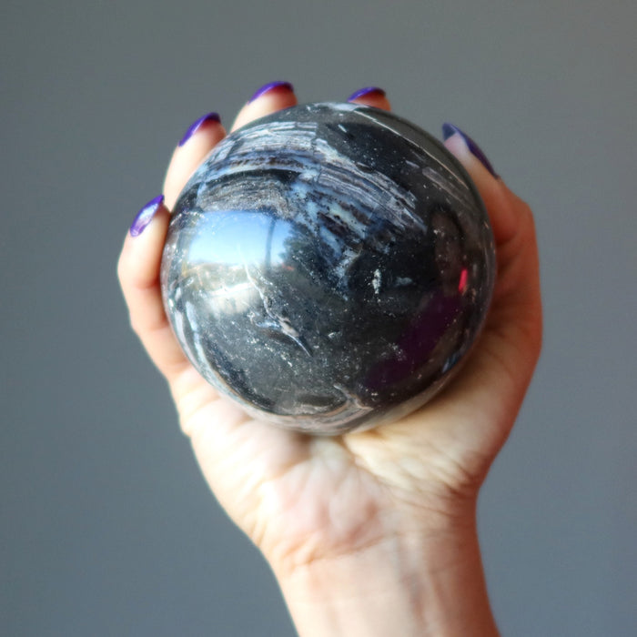 hand holding a Black Opal Sphere