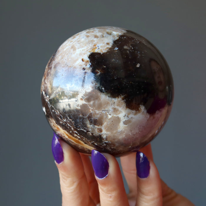 hand holding brown opal sphere