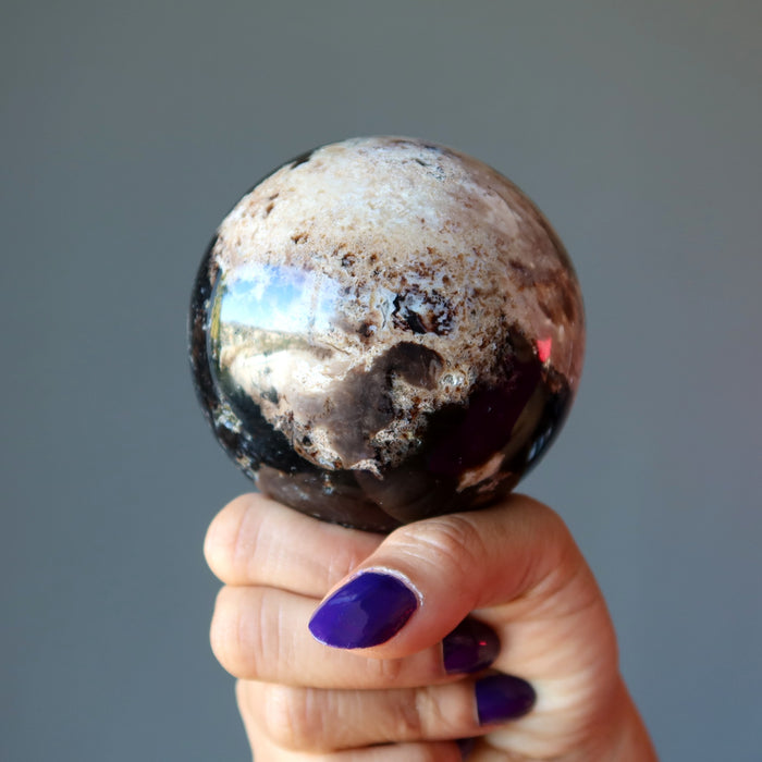 hand holding brown opal sphere