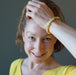 jamie of satin crystals with hand on her head wearing a round yellow opal beaded stretch bracelet