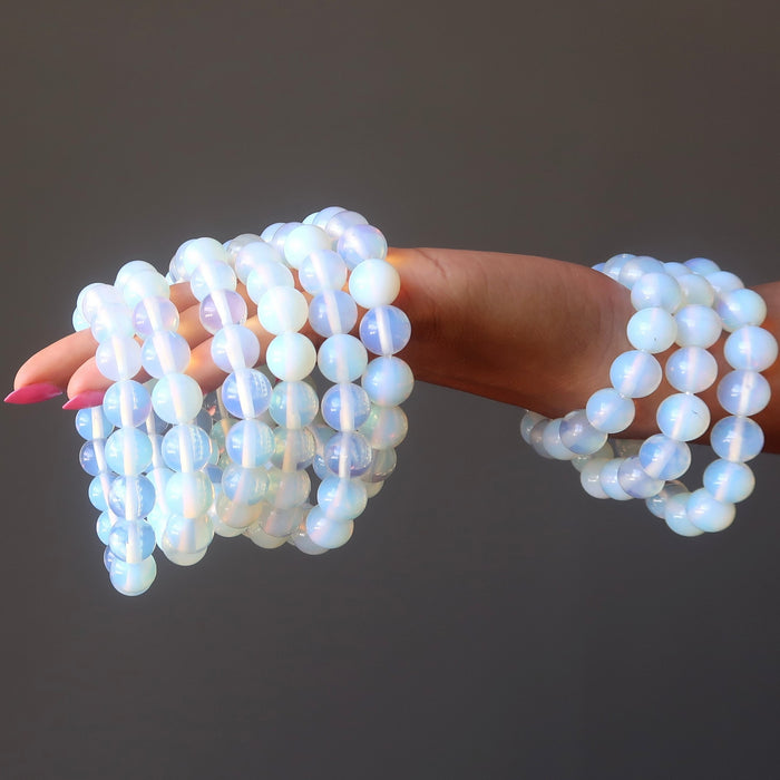 nine opalite bracelets held in the hand of a lady