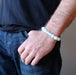  man with his hand on his jean pocket shows off the bright white opalite bracelet