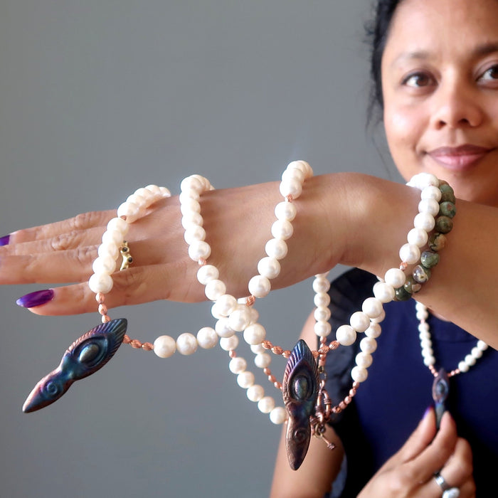 woman wearing and holding goddess pearl necklaces