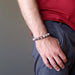 colorful red pietersite bead bracelet on a male model who holds his hands to his grey pants pocket