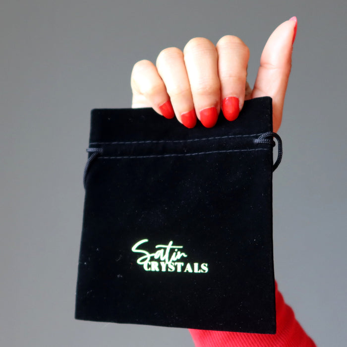 hand holding black velveteen pouch with gold "satin crystals" print