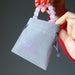 hands placing pink rose quartz jewelry in gray velvetten pouch with purple "satin crystals" print